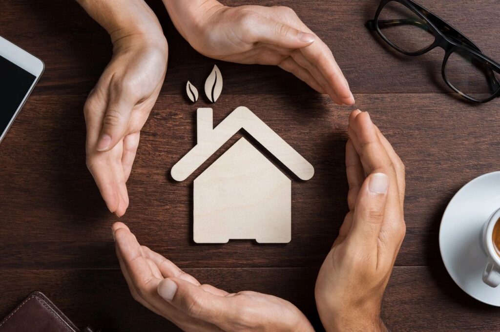 Image of Hands Surrounding Wooden Home Cutout